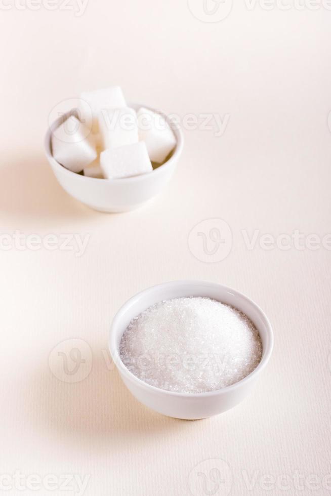 granulerad socker och socker kuber i skålar. välja mellan typer av socker. vertikal se foto