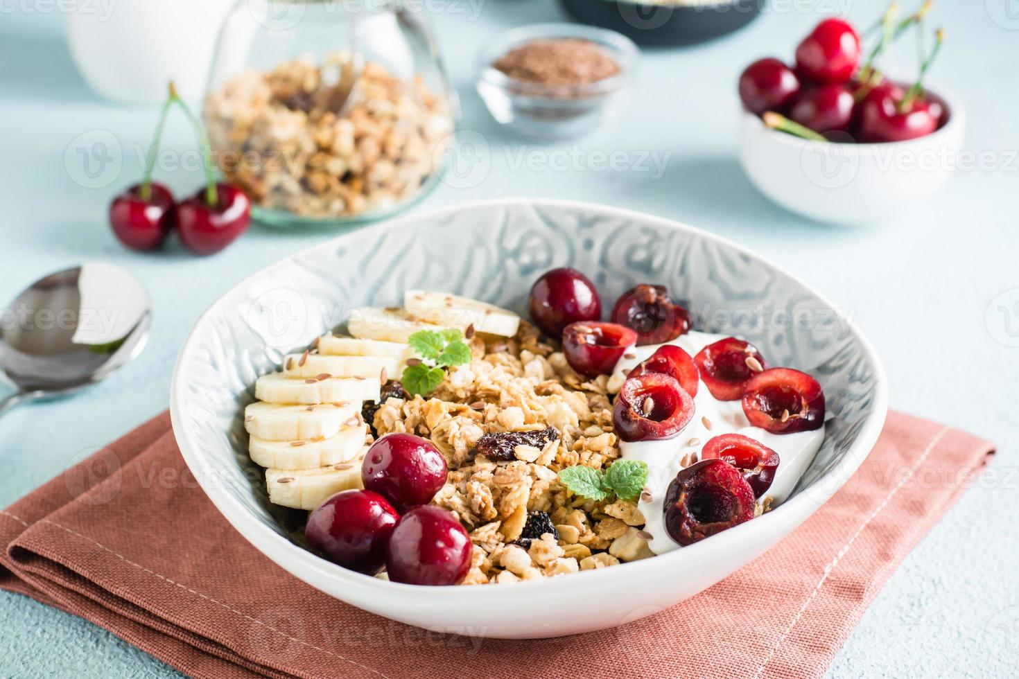 granola med körsbär, banan och lin frön i en skål på de tabell. hemlagad frukost foto