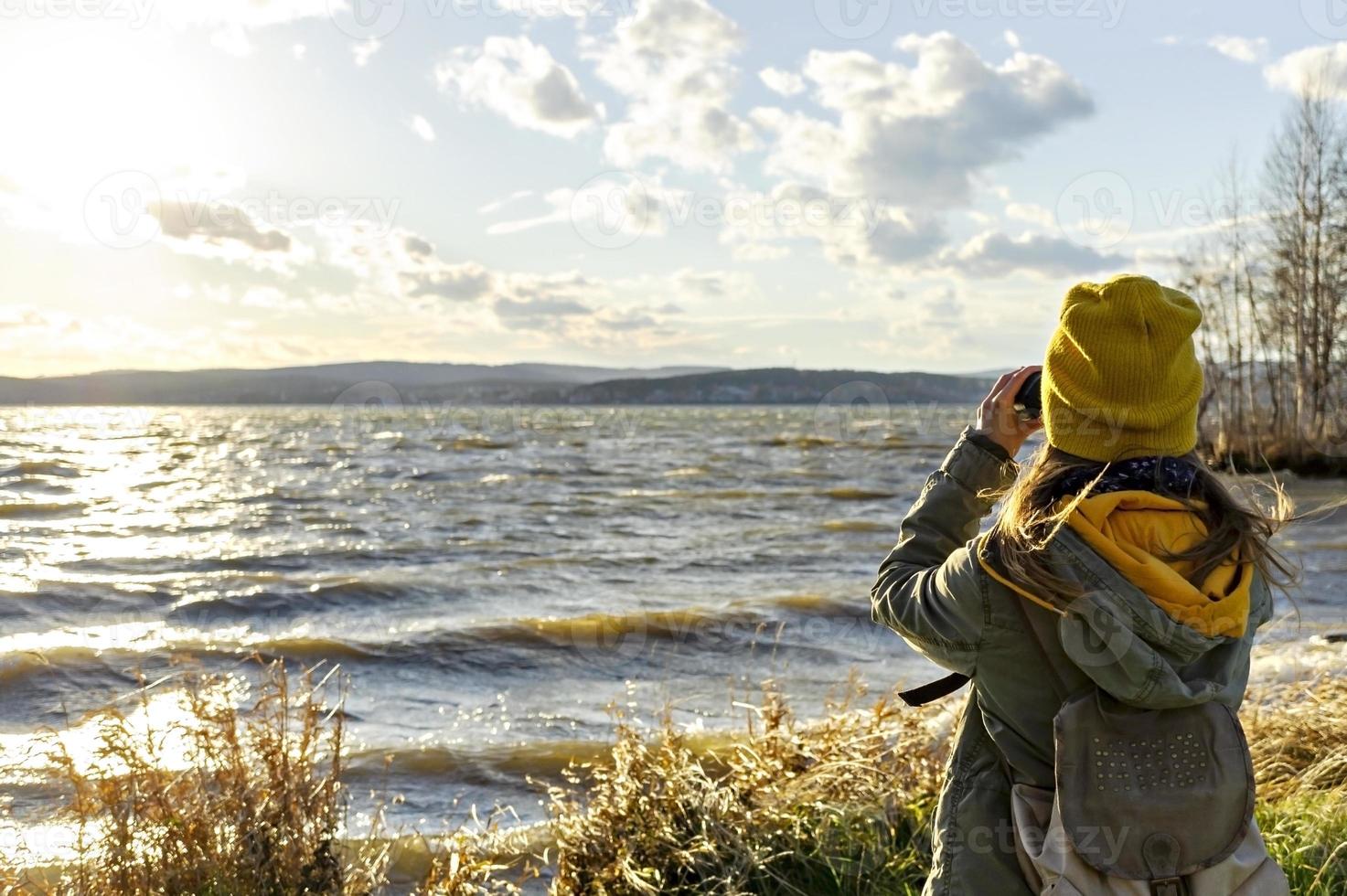 ung kvinna tittar på fåglar med binokulär på sjö. vetenskaplig forskning foto