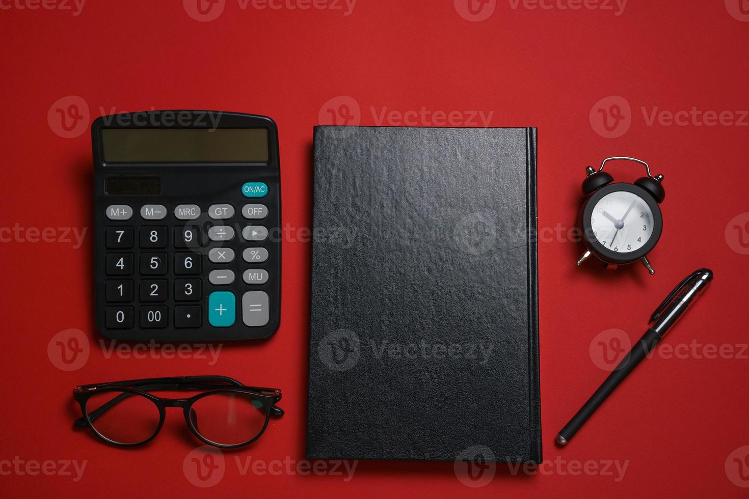 manlig svart anteckningsblock kulpenna penna och kalkylator, små larm klocka och glasögon foto