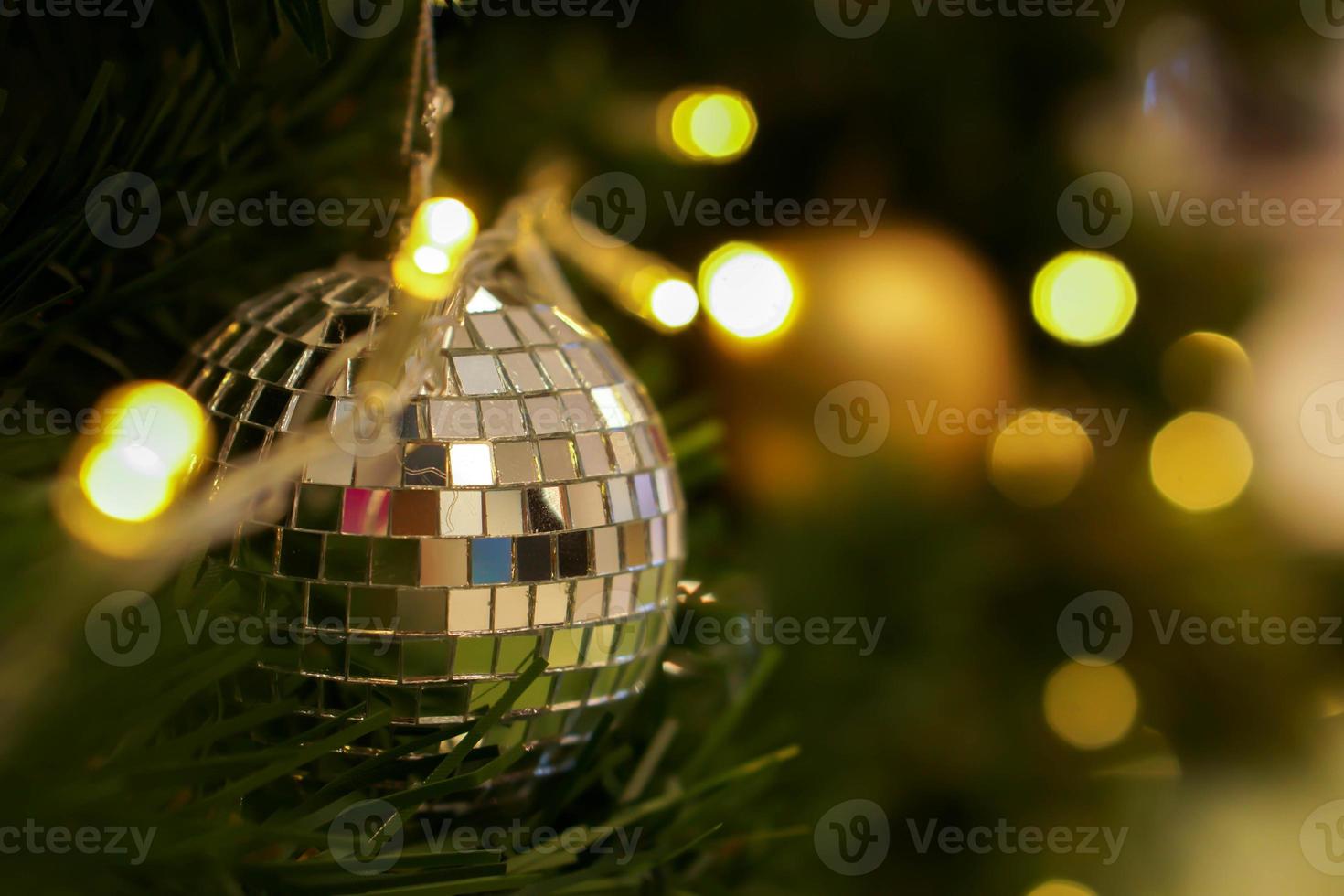 kristall boll dekorerad på tall träd på jul dag med suddigt bakgrund och bokeh av jul belysning. foto