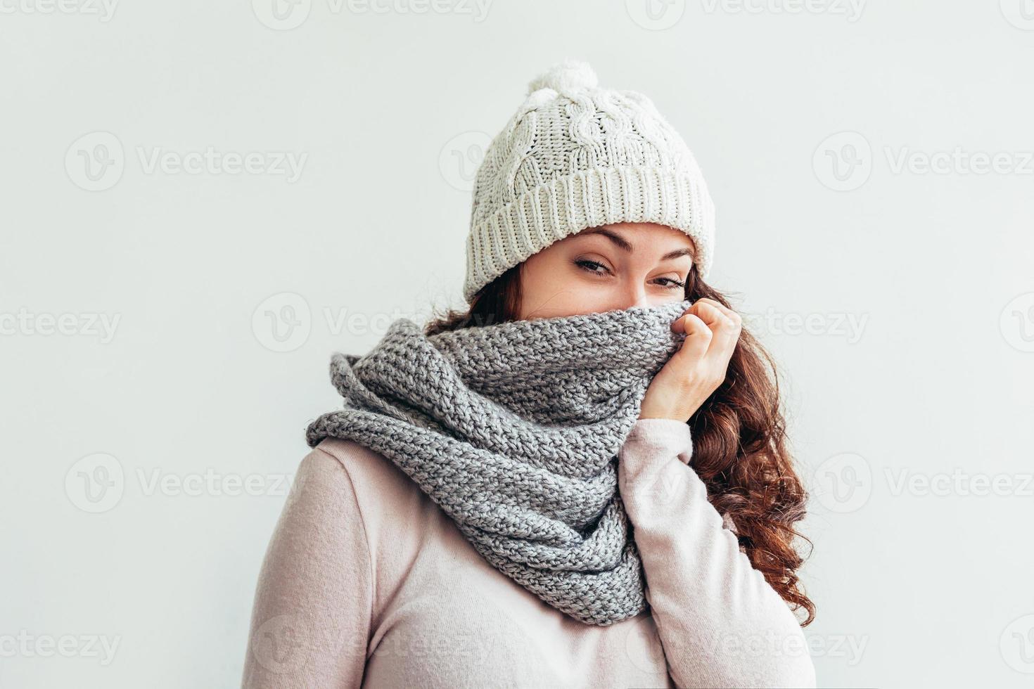 skrattande flicka bär värma kläder hatt och scarf isolerat på vit bakgrund foto