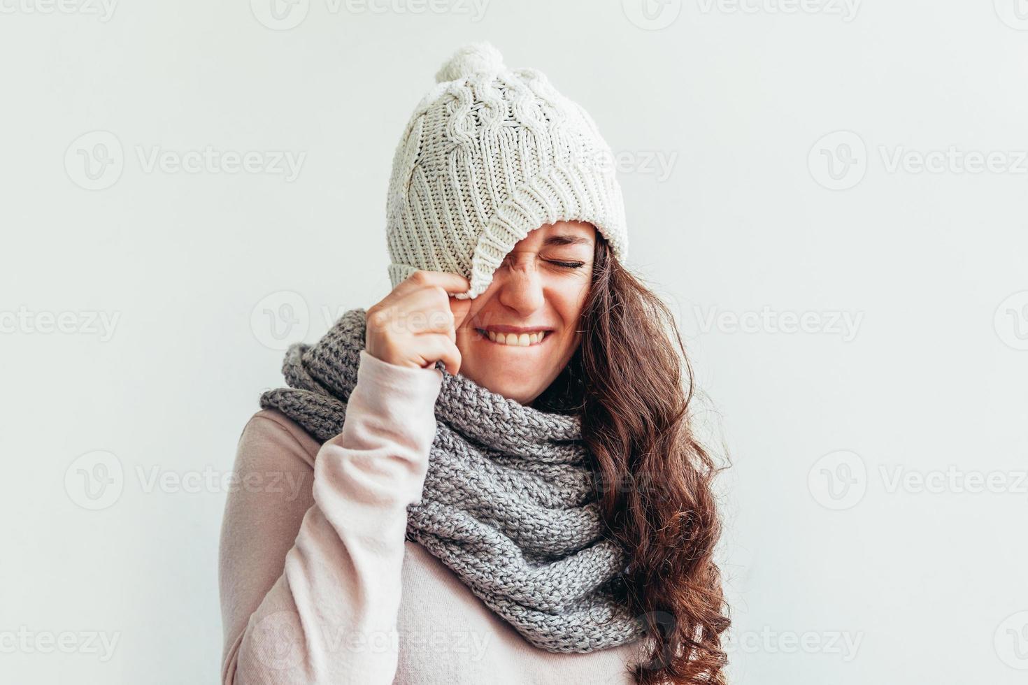 skrattande flicka bär värma kläder hatt och scarf isolerat på vit bakgrund foto