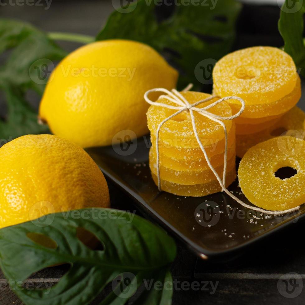 citron, orange och grapefrukt skivor i socker isolerat på en trä- bakgrund, närbild. marmelad sötsaker. sötsaker med citrus- smak. godis foto