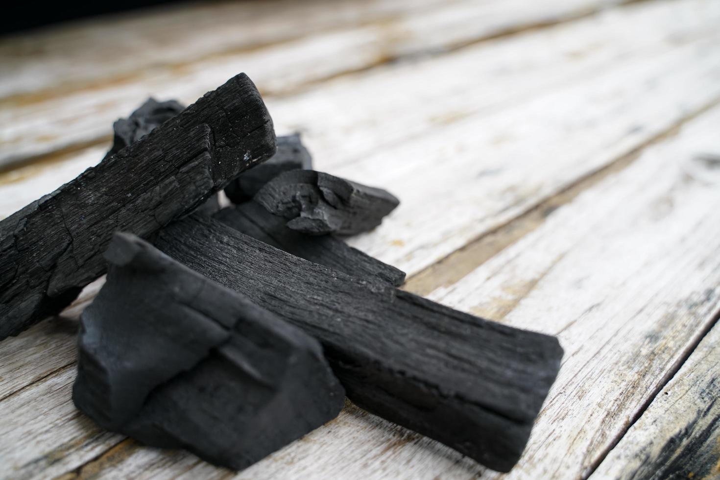 svart träkol på gammal trä bakgrund, träkol är grundläggande i grillning. foto