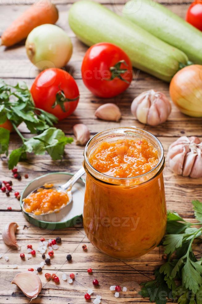 hemlagad kaviar från zucchini tomater och lök i en glas burk på en trä- bakgrund. hemlagad produktion konservering, konserverad stuvad grönsak. foto