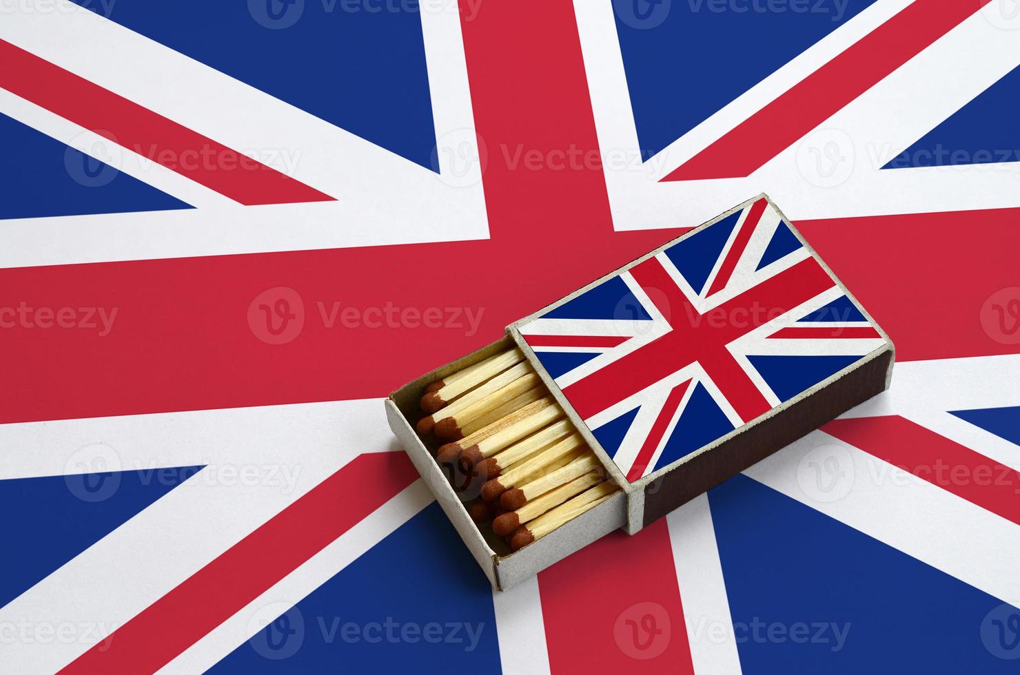 bra storbritannien flagga är visad i ett öppen tändsticksask, som är fylld med tändstickor och lögner på en stor flagga foto