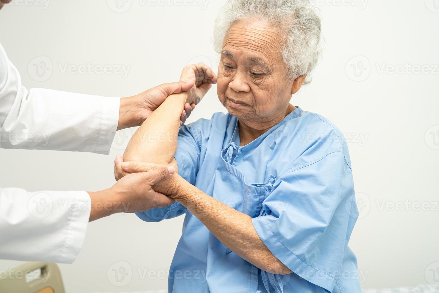 asiatisk senior eller äldre gammal damkvinnapatient känner smärta hennes armbåge på sängen på vårdavdelningen, hälsosamt starkt medicinskt koncept. foto