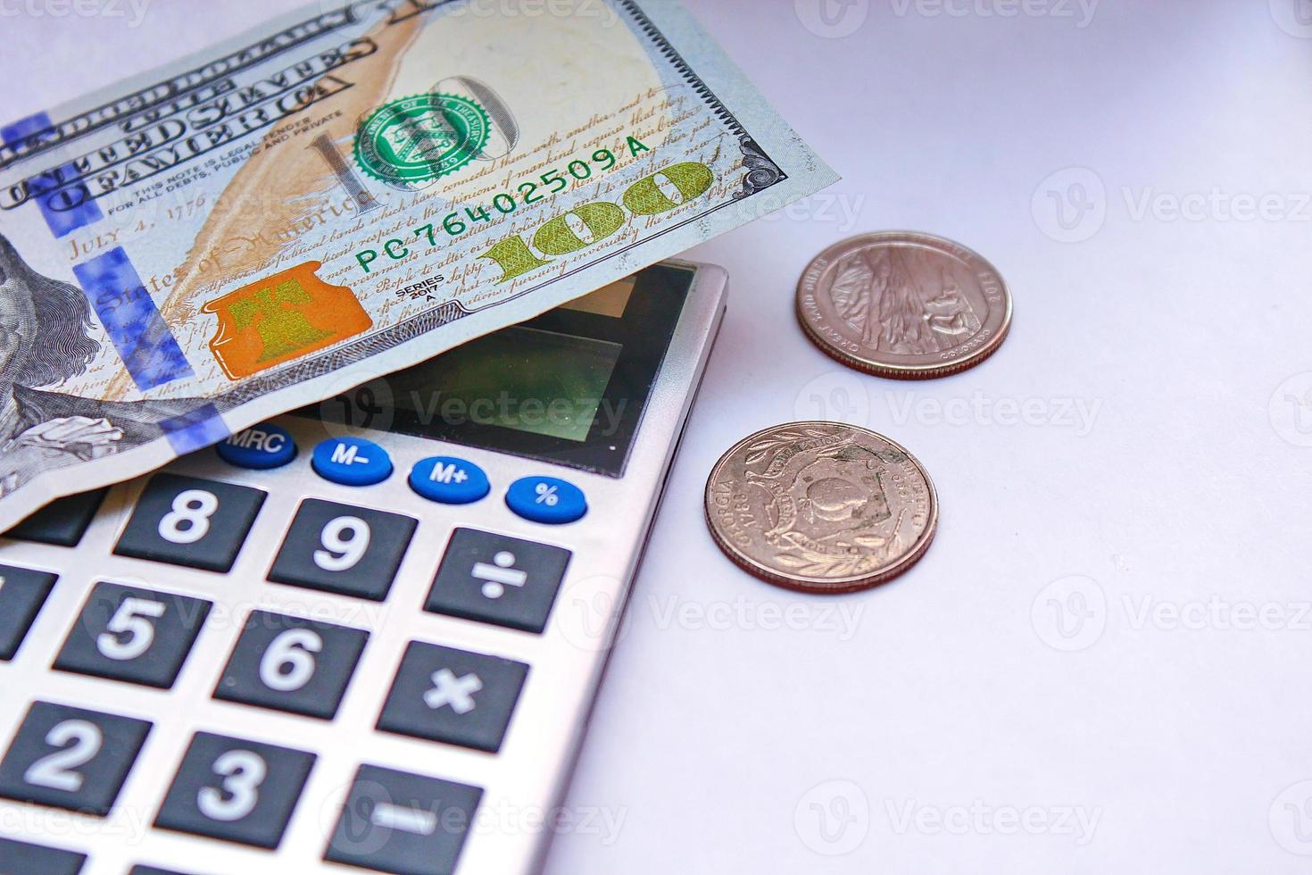 kalkylator och dollar räkningar är placerad på en vit tabell. foto