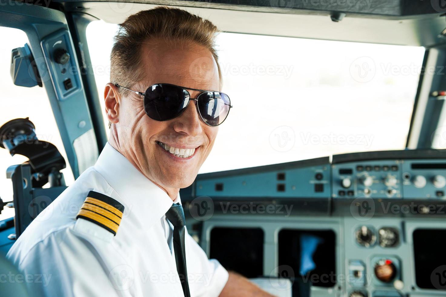 pilot i cockpit. bak- se av självsäker manlig pilot ser över axel och leende medan Sammanträde i cockpit foto