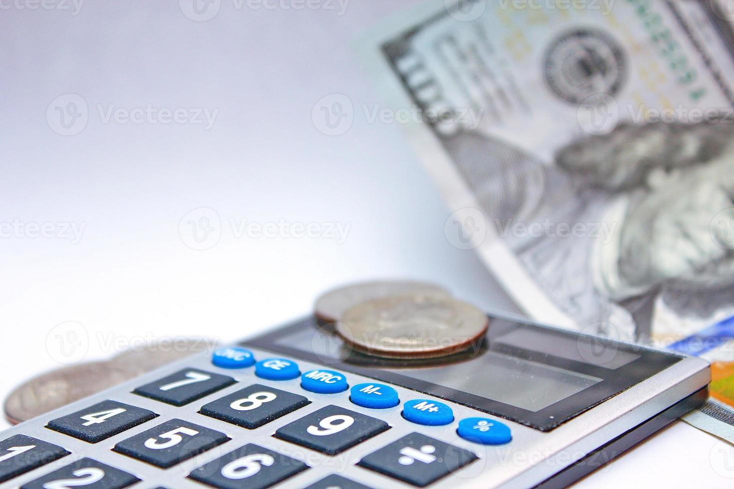 kalkylator och dollar räkningar är placerad på en vit tabell. foto