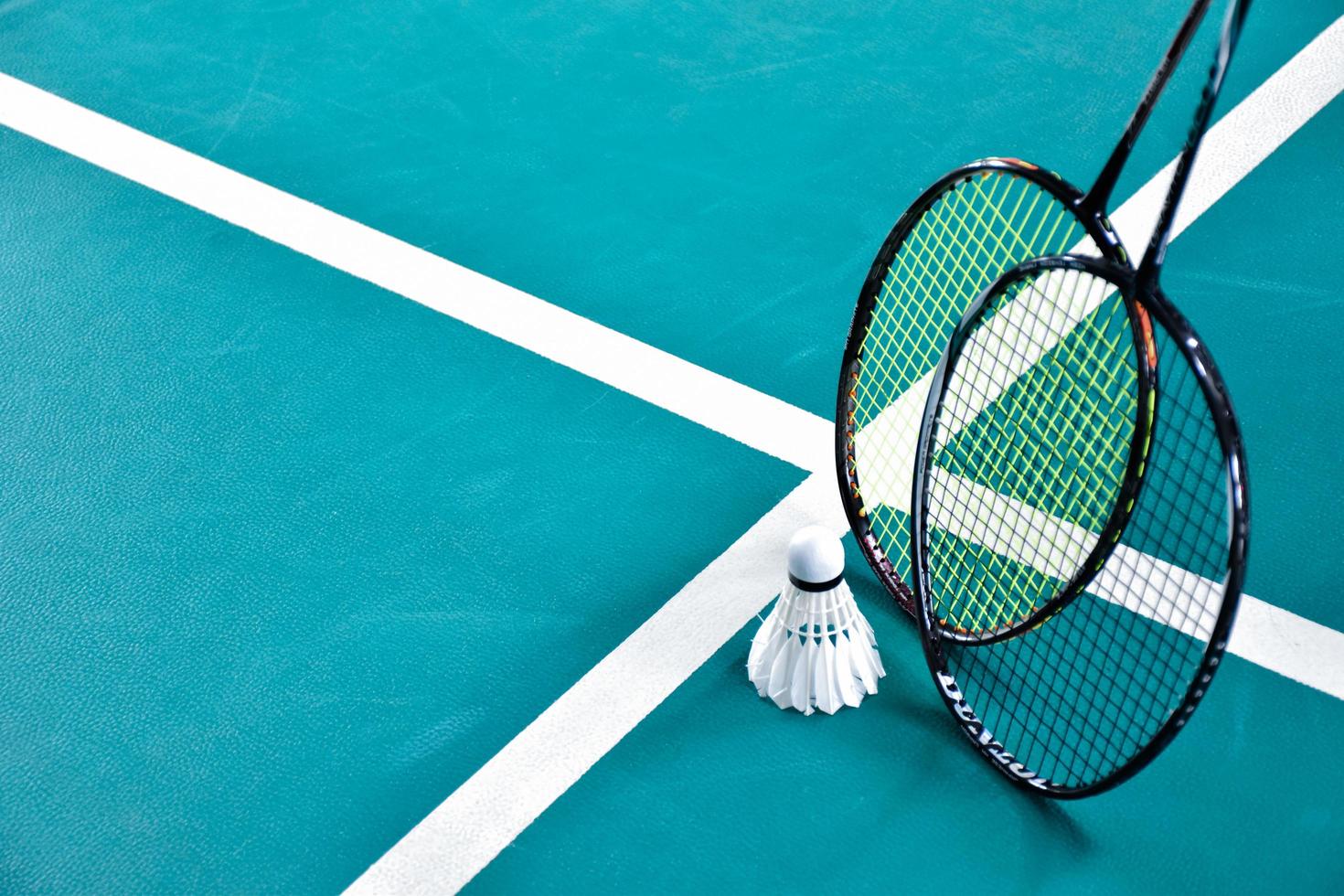 grädde vit badminton fjäderboll och racket på golv i inomhus- badminton domstol, kopia Plats, mjuk och selektiv fokus på fjäderbollar. foto