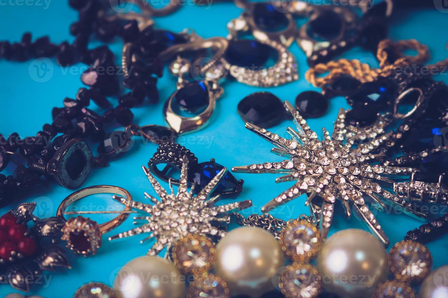 skön dyrbar skinande smycke trendig glamorös Smycken uppsättning, halsband, örhängen, ringar, kedjor, broscher med pärlor och ruter på en blå bakgrund. platt lägga, topp se, kopia plats foto