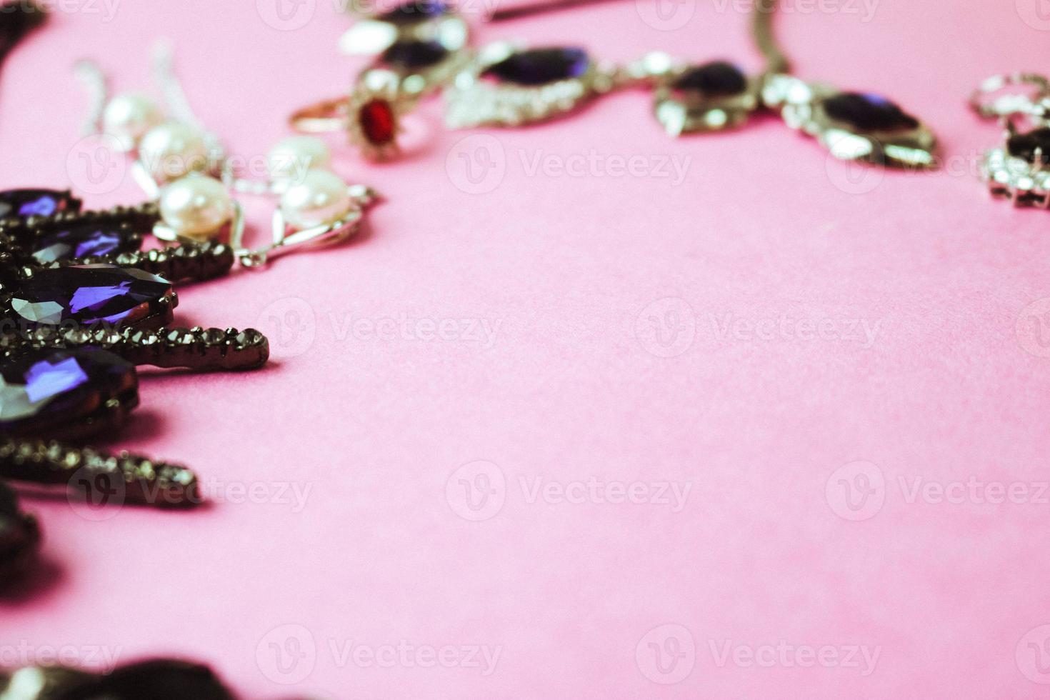 skön dyrbar skinande smycke trendig glamorös Smycken uppsättning, halsband, örhängen, ringar, kedjor, broscher med pärlor och ruter på en rosa lila bakgrund. platt lägga, topp se, kopia plats foto