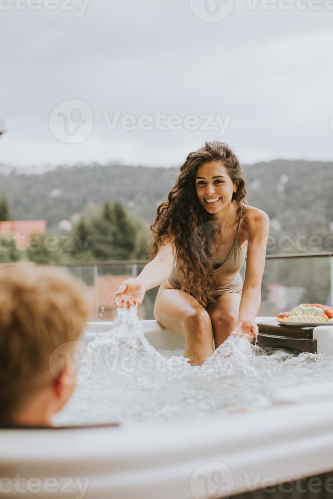 ung par njuter i utomhus- varm badkar på semester foto