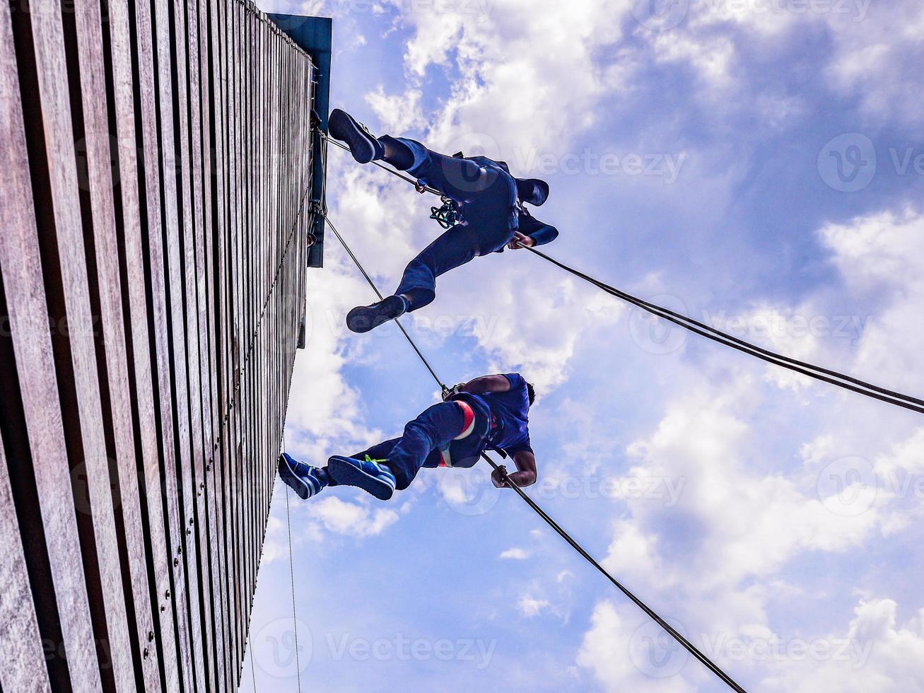 två ungdom glidning ner de utomhus- klättrande torn foto
