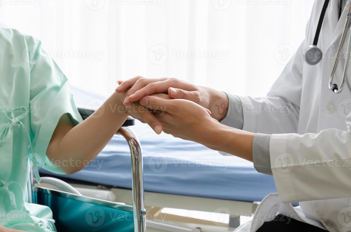 manlig läkare innehav kvinna patient hand för uppmuntran i sjukhus rum. patient skaffa sig deprimerad, påfrestning, ledsen på rullstol. foto