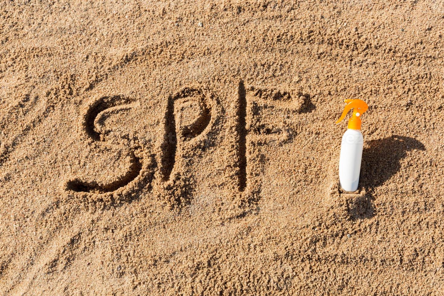 Sol skydda faktor. spf ord skriven på de sand och vit flaska med solbränna grädde. hud vård begrepp bakgrund foto