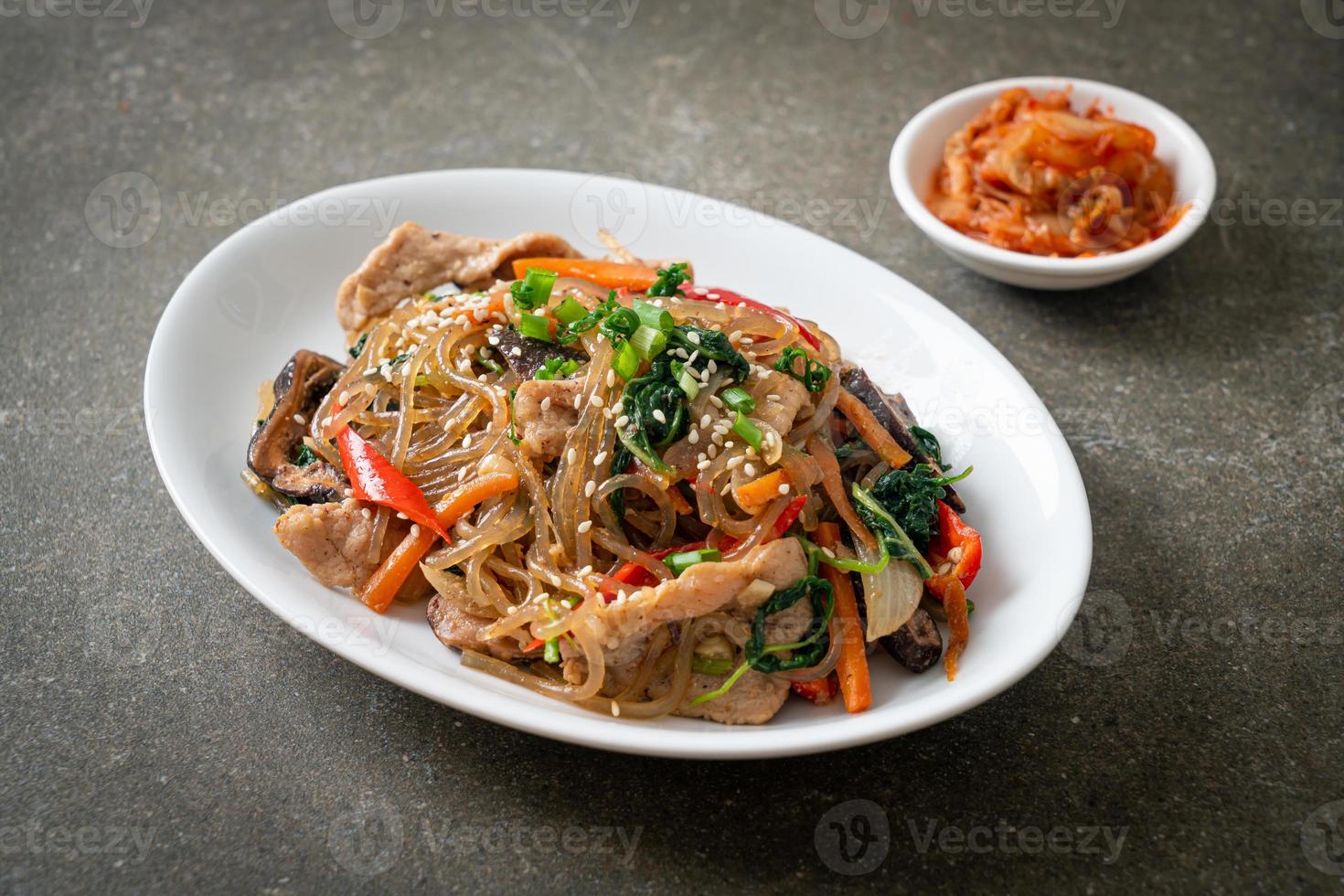 japchae eller wokade koreanska vermicelli nudlar med grönsaker och fläsk toppad med vit sesam foto