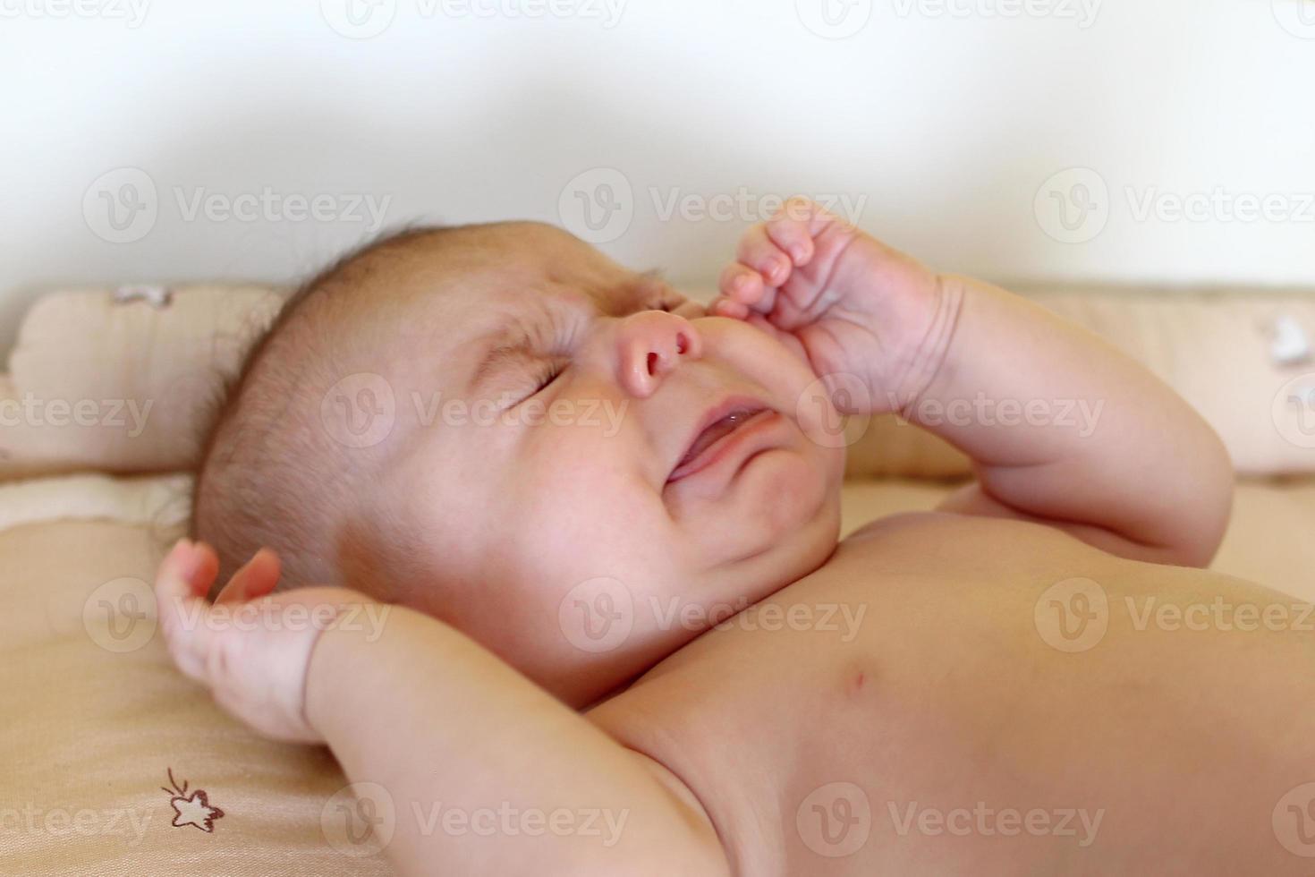 nyfödd bebis flicka är liggande på ändring tabell och gråt. foto