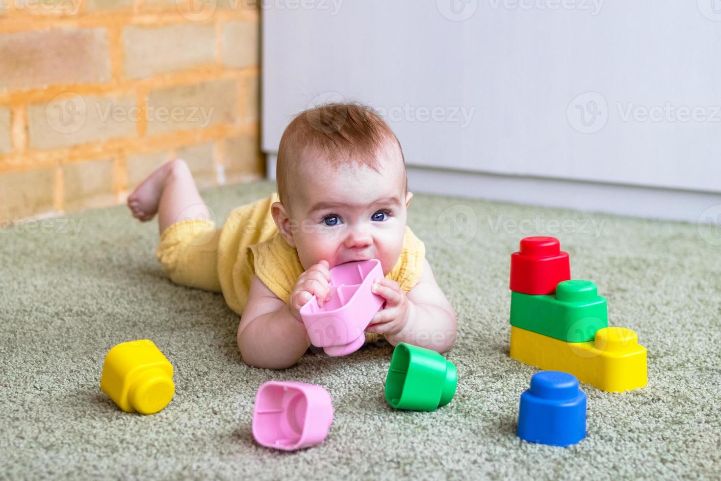 uppriktig livsstil porträtt av liten flicka. litet barn barn spelar med mjuk plast färgrik konstruktör. foto