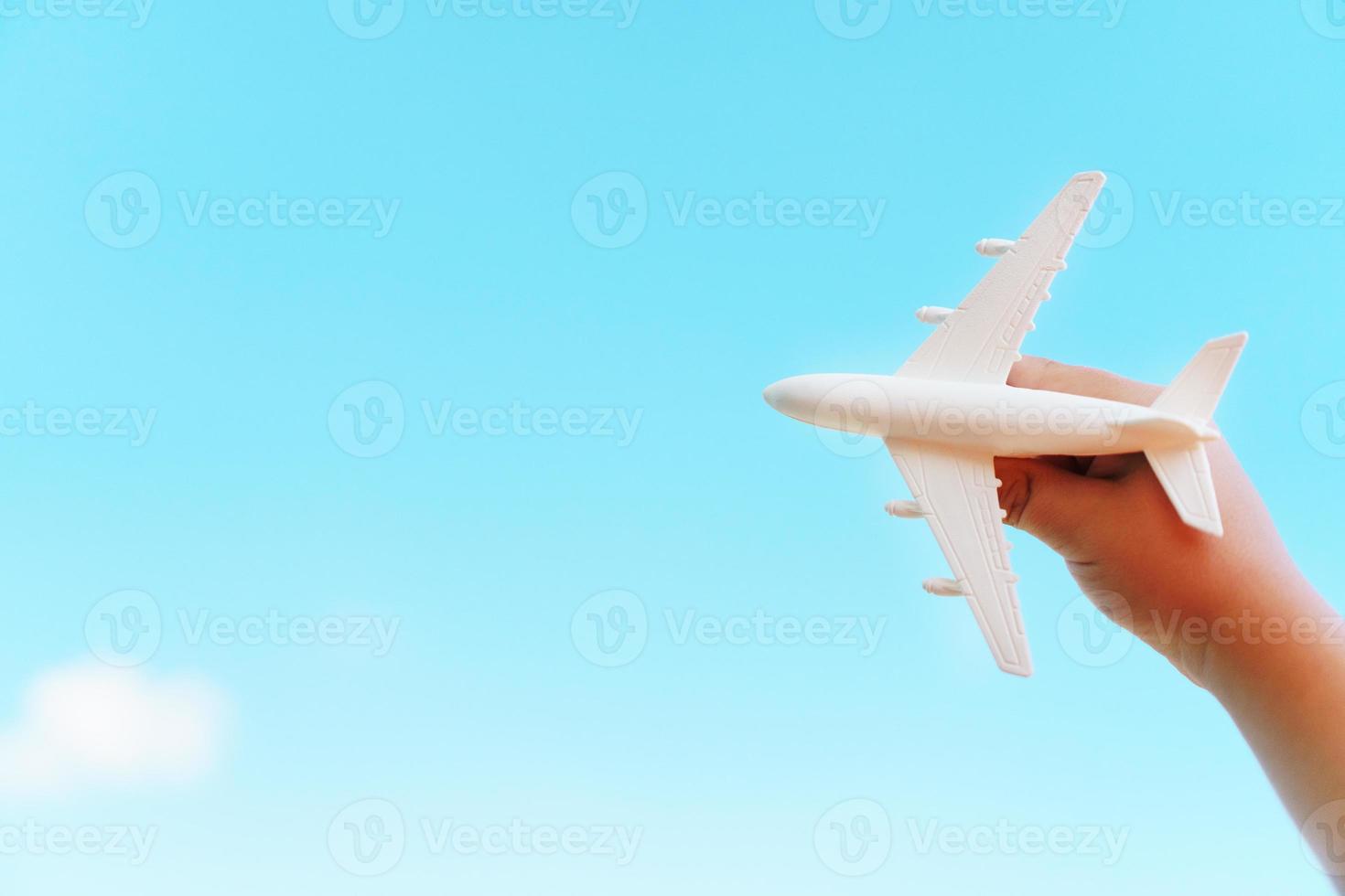 en vit flygplan i en barnets hand mot en blå himmel. de begrepp av en dröm av resa och flyg. foto