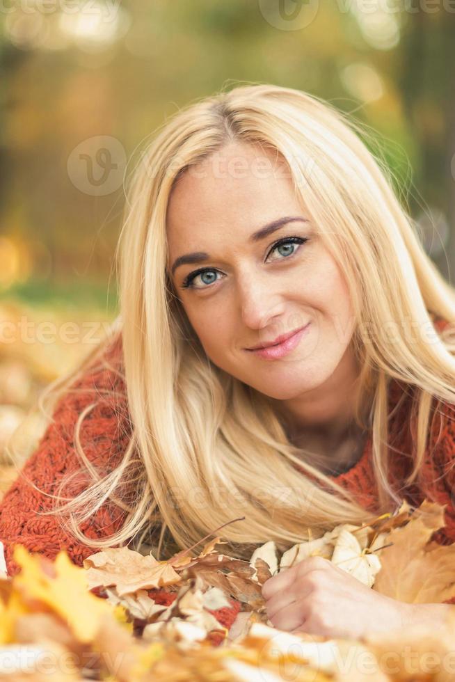 kvinna lögner ner på löv på de höst parkera foto