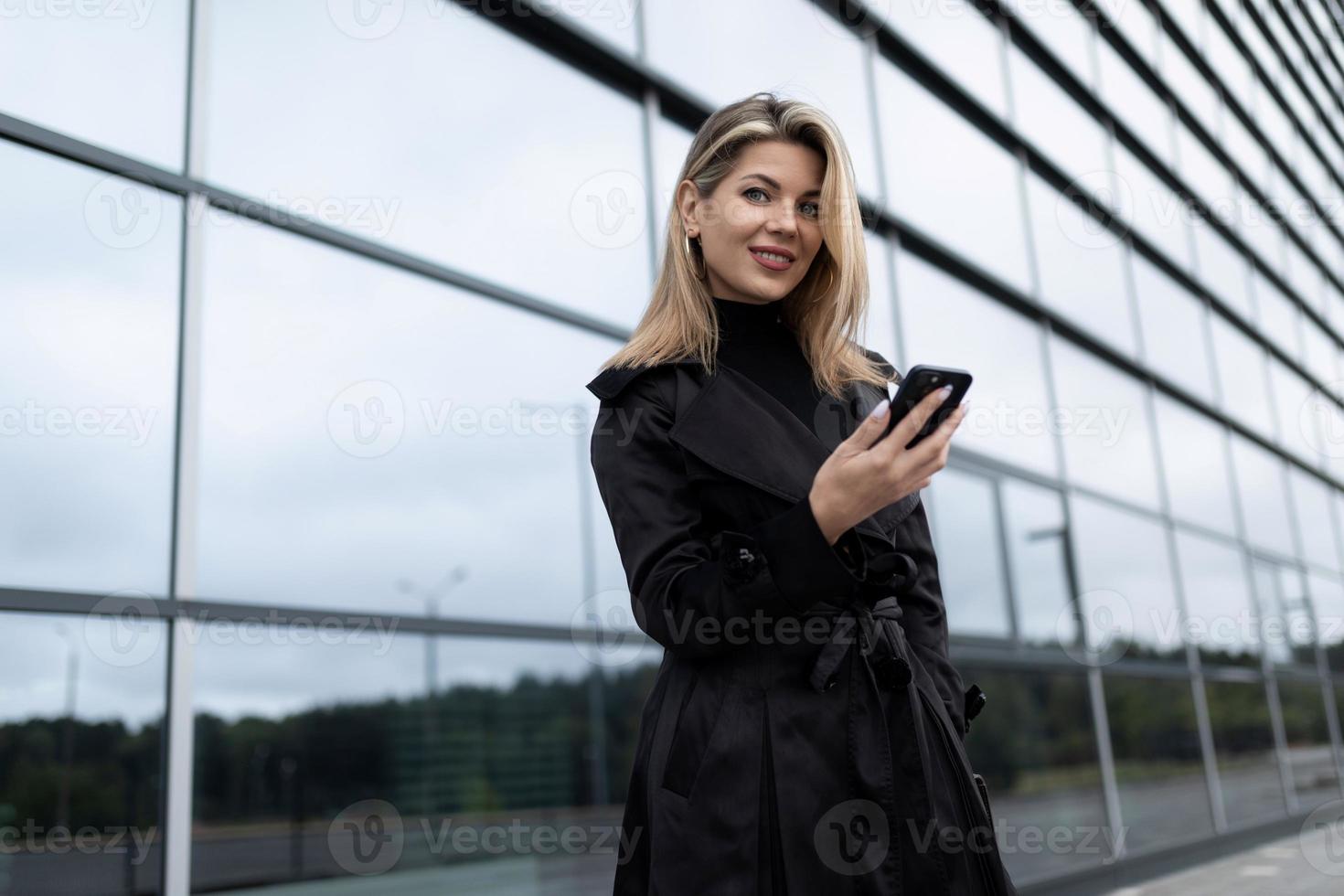 företag korrespondens medelålders affärskvinna på de bakgrund av en glas kontor byggnad foto