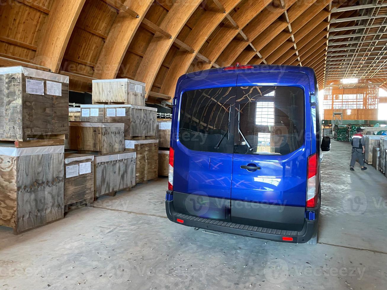 en blå minibus i en lager för industriell Utrustning och material. begrepp leverans, logistik, incoterms dapp, dpp villkor av leverans foto