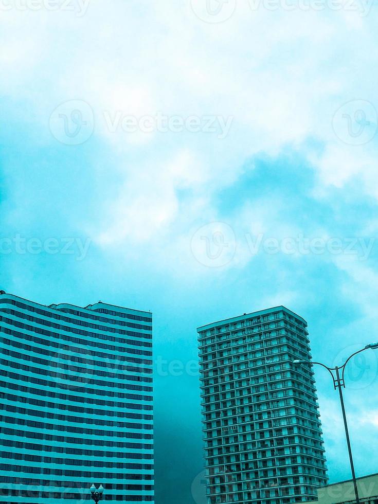 en lång, ljus lägenhet byggnad i de stad Centrum. höghus bostads- byggnad i vit mot en blå ljus himmel. nära en blå hus i de form av en Vinka. ny fjärdedel i de stad foto