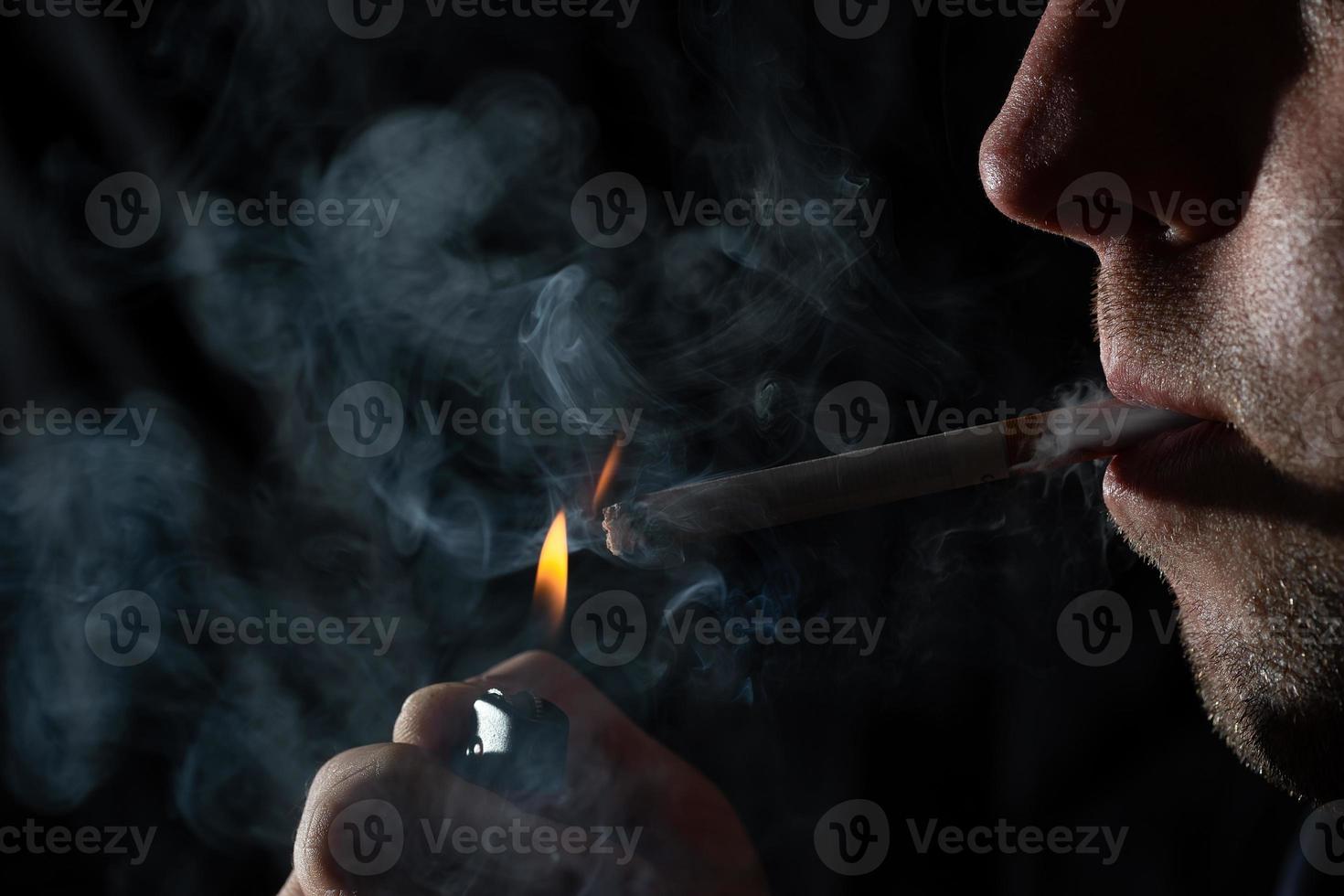 närbild ung man röker en cigarett. foto