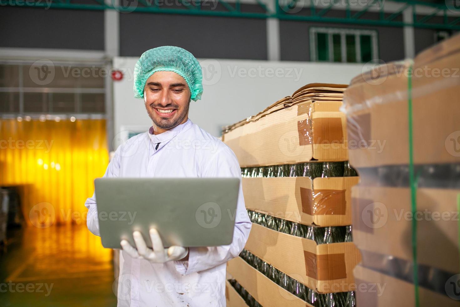 arbetstagare med bärbar dator är kontroll produkt på de produktion linje i de dryck fabrik. tillverkare checkar kvalitet av mat industri. foto
