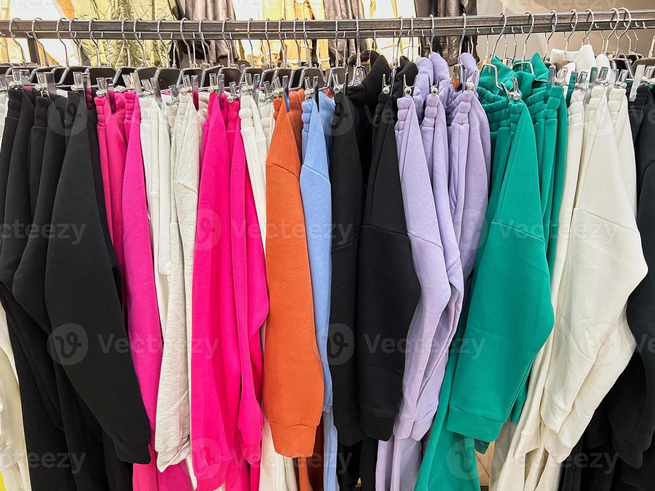 Kläder utställning i små affär. kläder hängande på galgar. foto