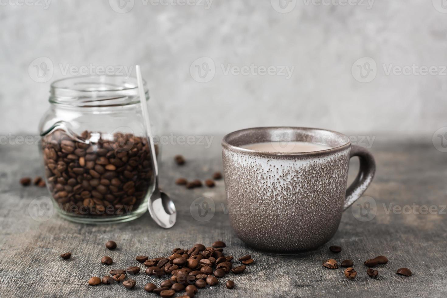 latte i en keramisk kopp och burk med kaffe bönor på de tabell. tid för en ha sönder och avslappning foto