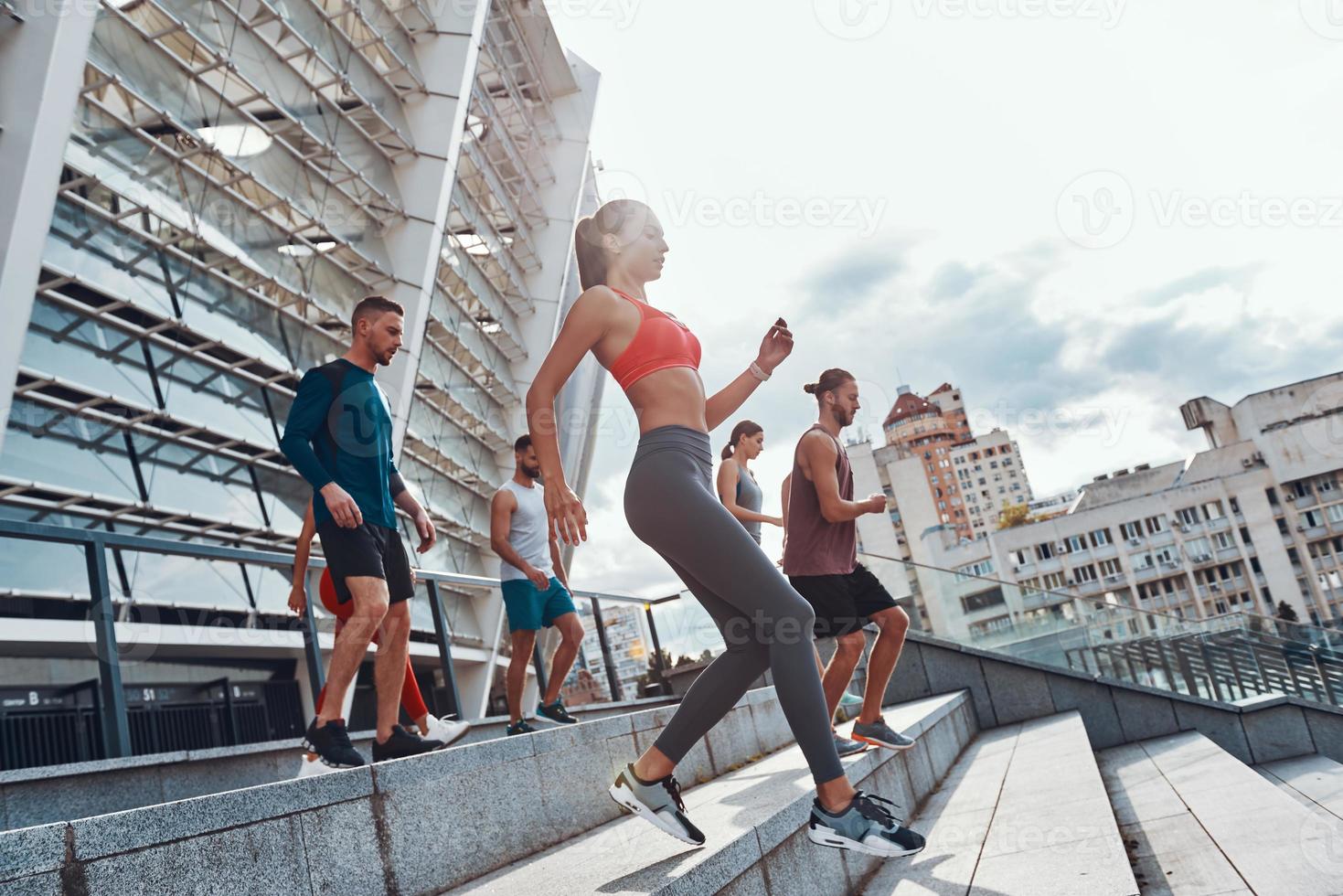 grupp av ung människor i sporter Kläder joggning medan utövar på de trappa utomhus foto