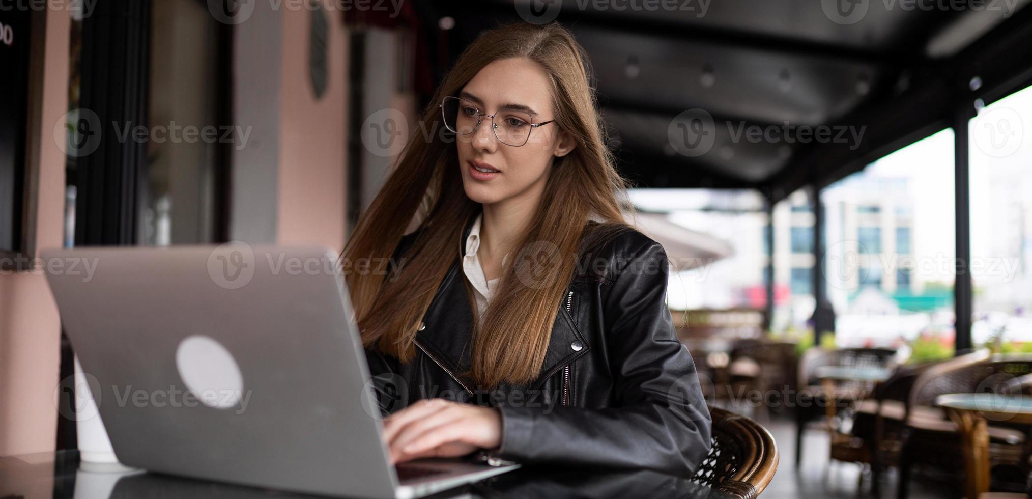 kvinna frilansare arbetssätt uppkopplad på bärbar dator i stad Kafé foto