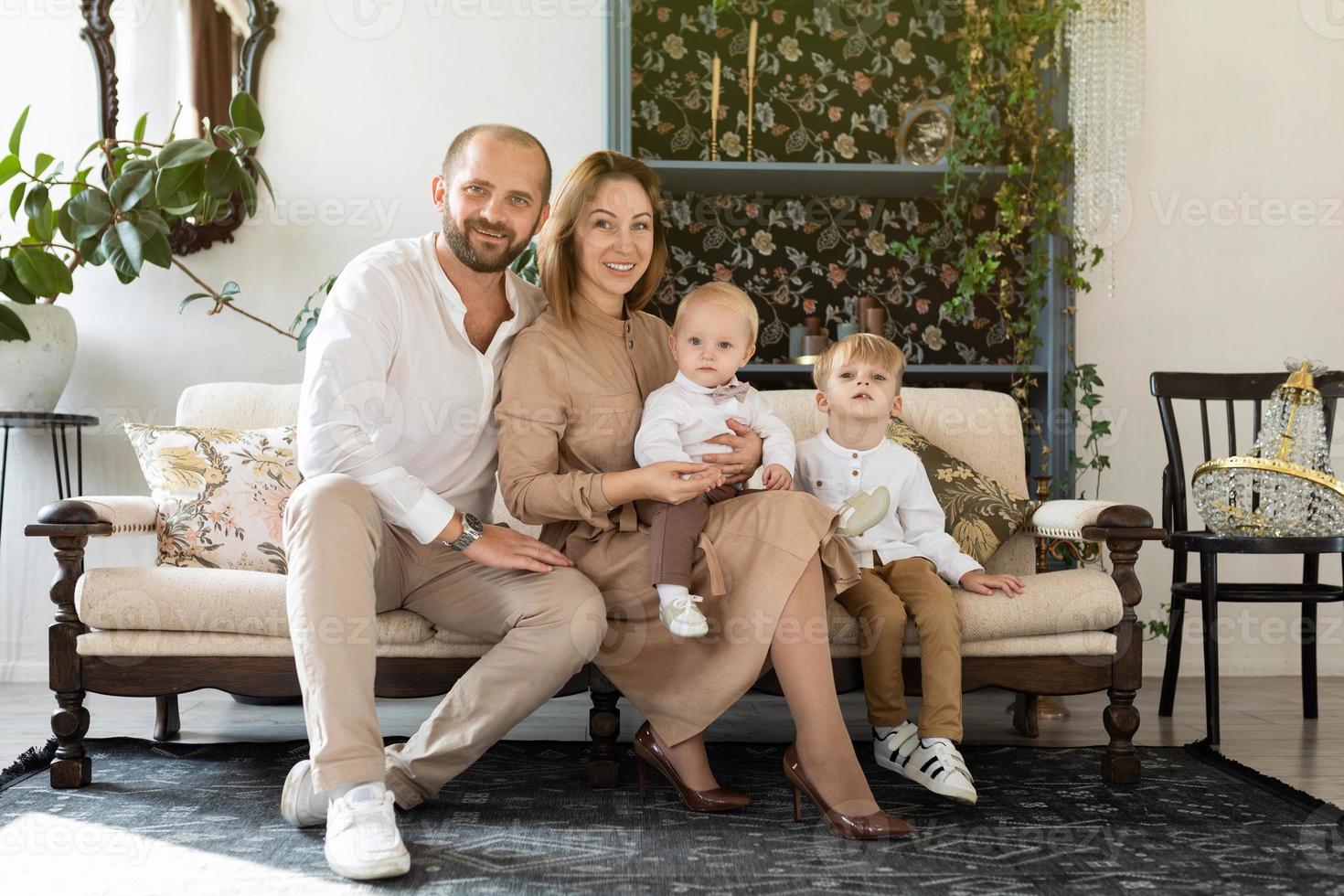Lycklig europeisk familj med två liten pojke barn Sammanträde på soffa i eleganta rum foto