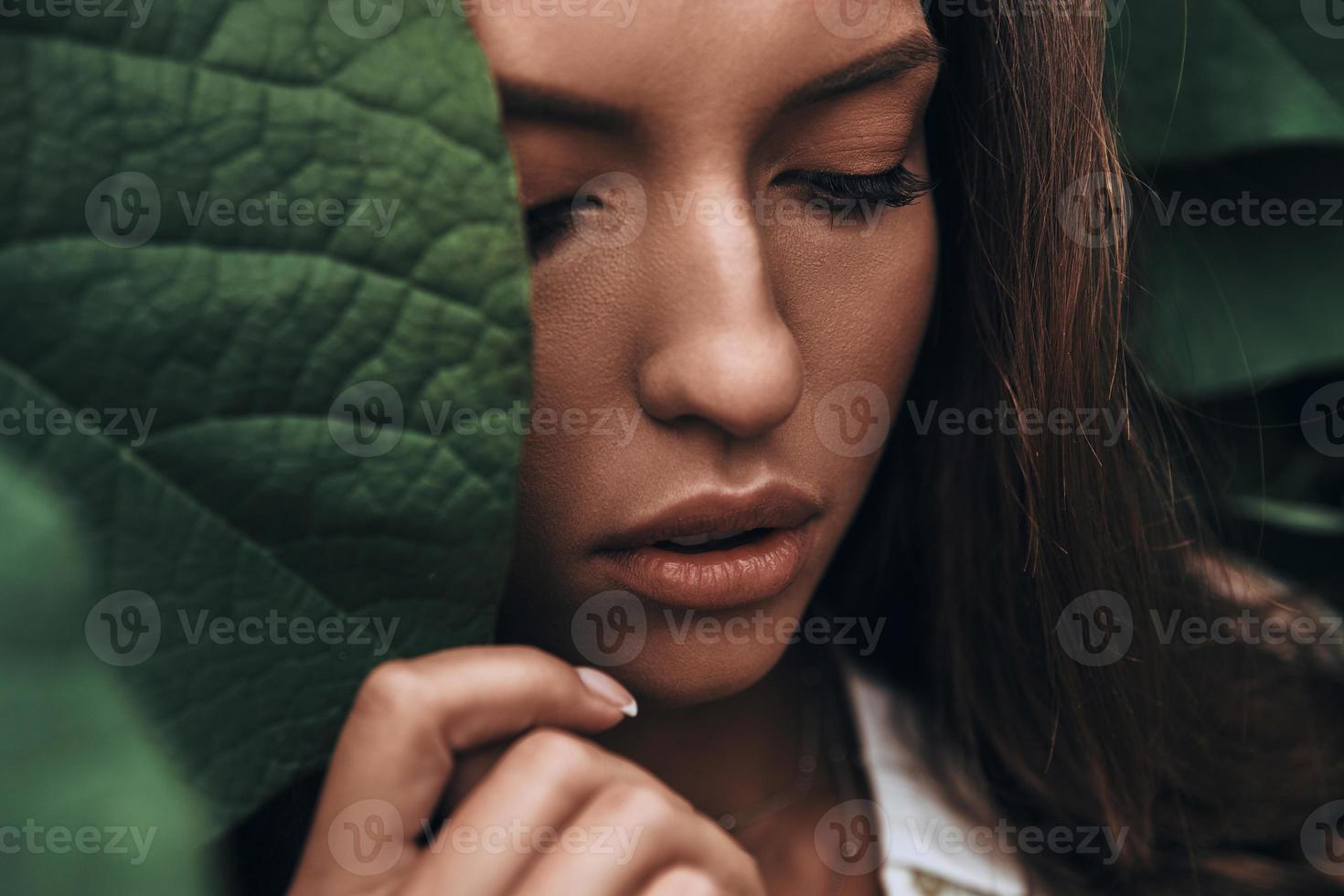 otroligt skön. attraktiv ung kvinna ser ner medan stående bland de löv utomhus foto