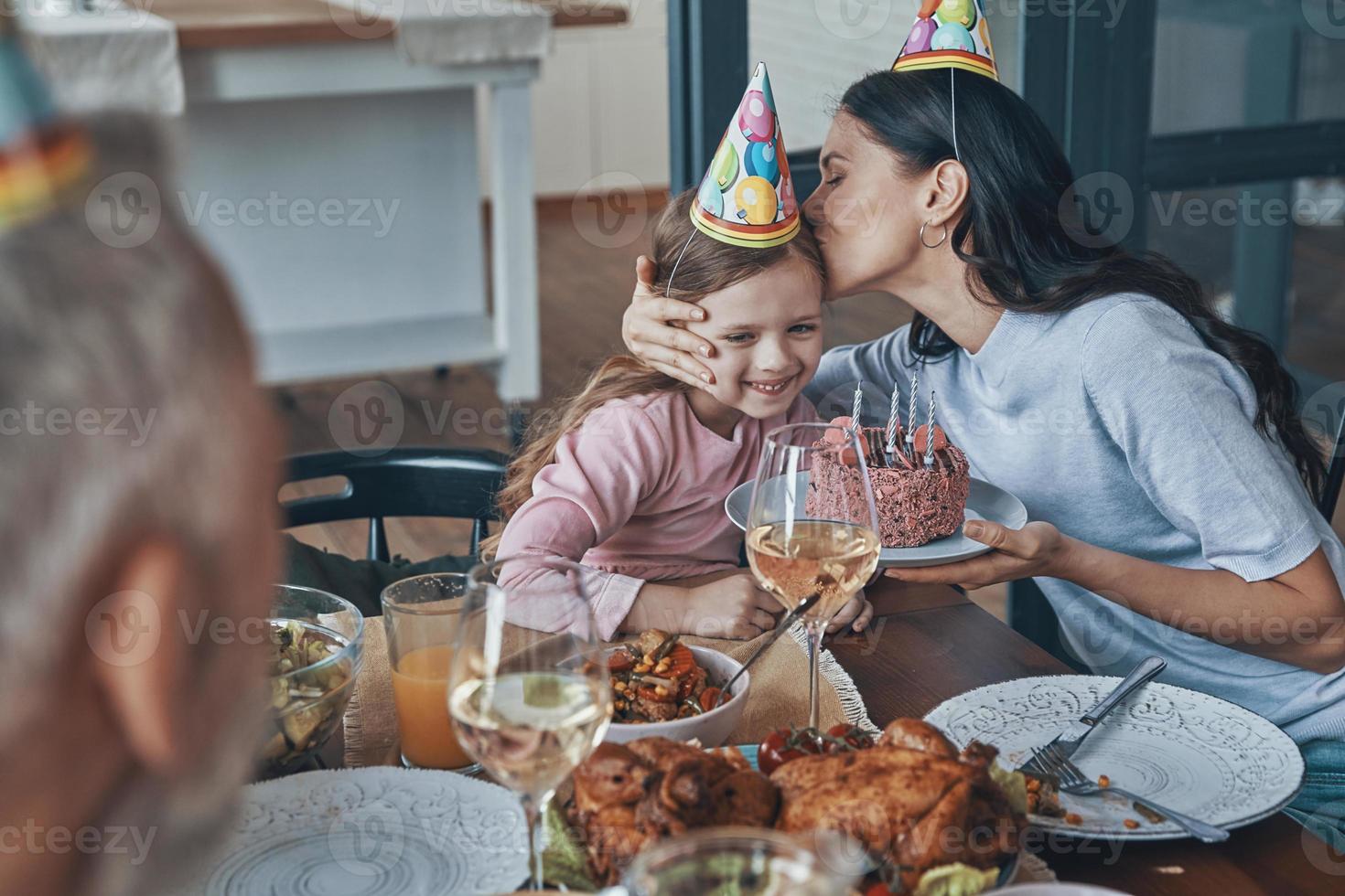 Lycklig familj fira födelsedag av liten flicka medan Sammanträde på de dining tabell på Hem foto