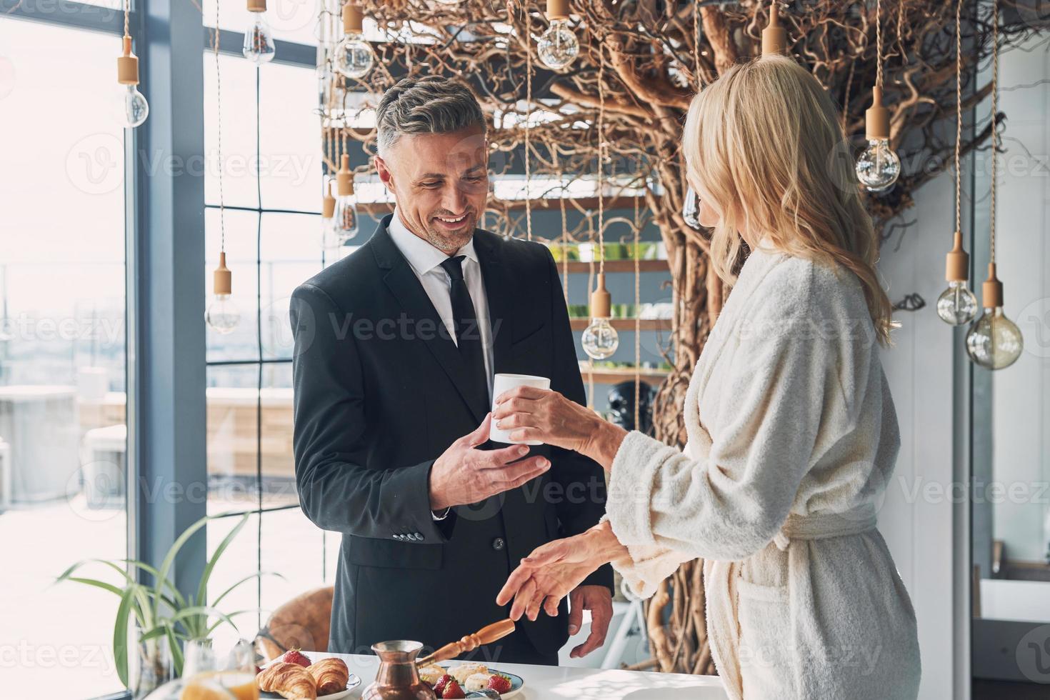 skön mogna par njuter frukost tillsammans medan utgifterna tid i de inhemsk kök foto