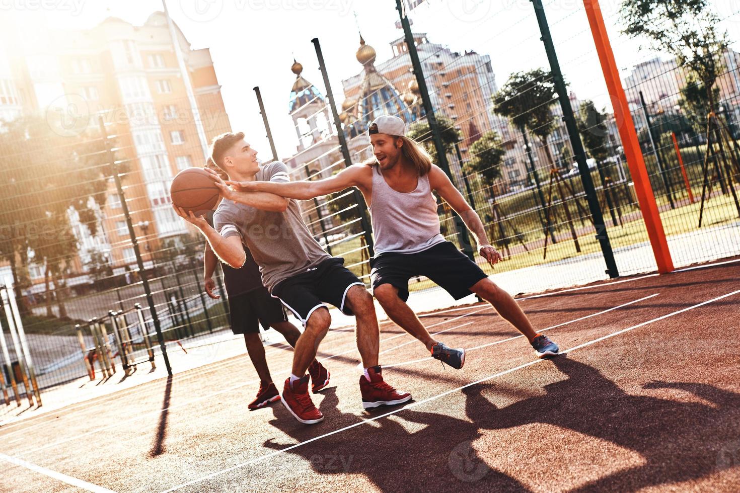 Lycklig till spela. grupp av ung män i sporter Kläder spelar basketboll och leende medan utgifterna tid utomhus foto