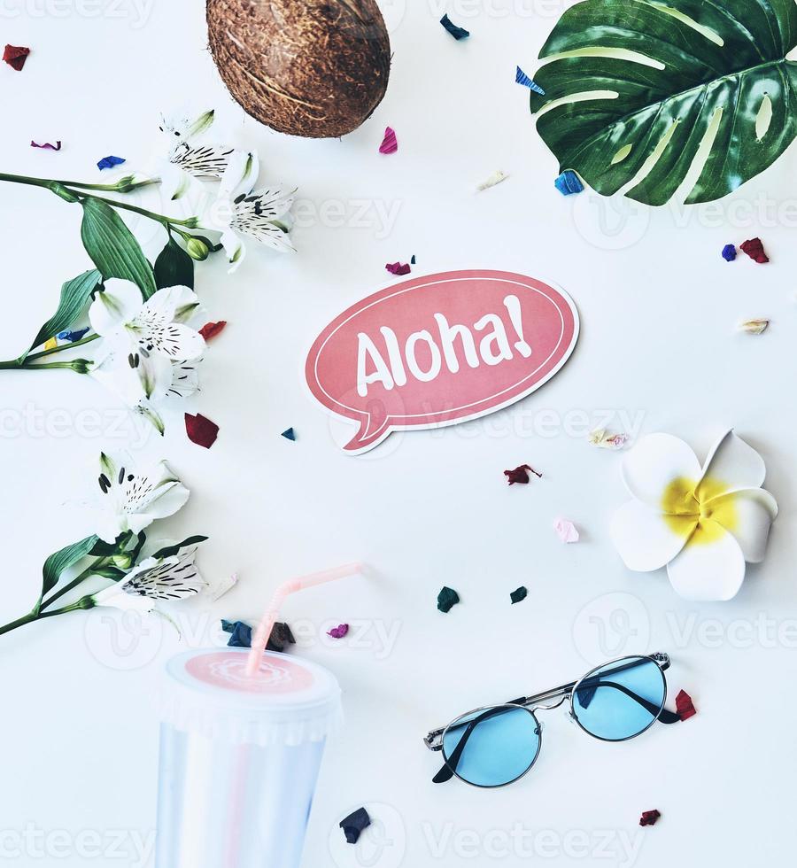 Hej sommar hög vinkel skott av glasögon, kokos och blomma liggande mot vit bakgrund foto