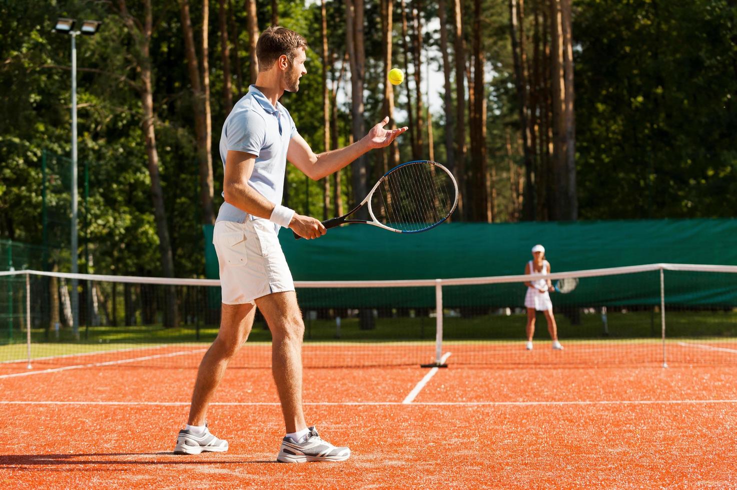 framställning till hans bäst tjäna. full längd av man och kvinna spelar tennis på tennis domstol foto