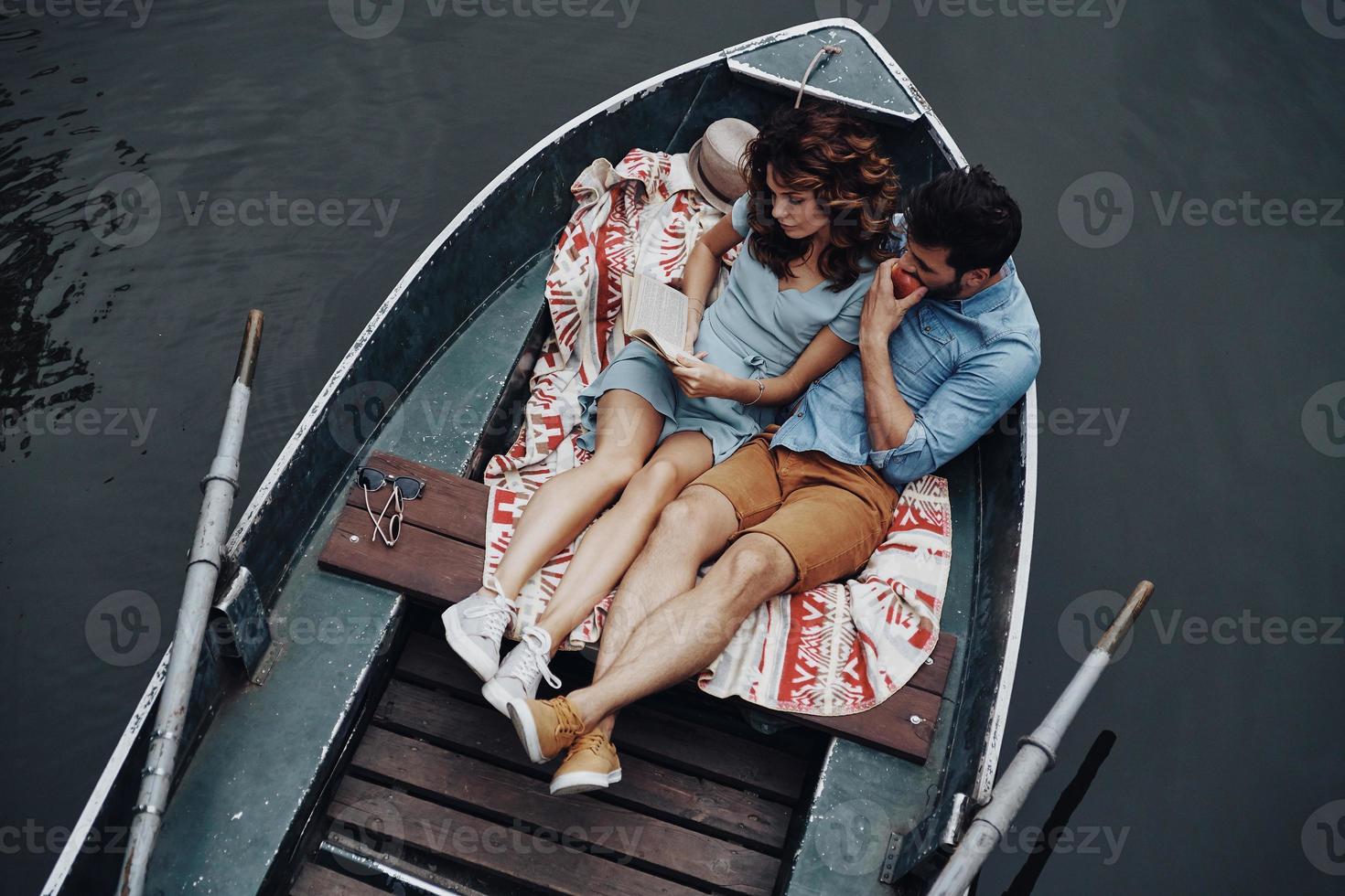 känsla mysigt tillsammans. topp se av skön ung kvinna läsning bok medan Sammanträde i de båt med henne pojkvän foto