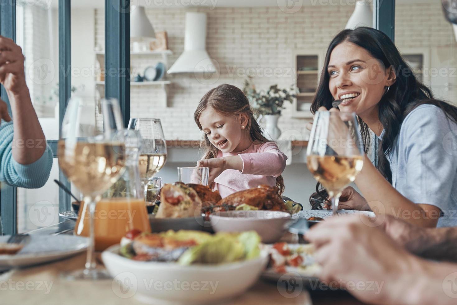 Lycklig familj kommunicerar och leende medan har middag tillsammans foto