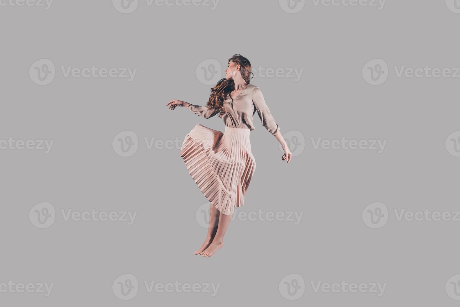 levitation. studio skott av attraktiv ung kvinna i skön klänning svävande i luft foto