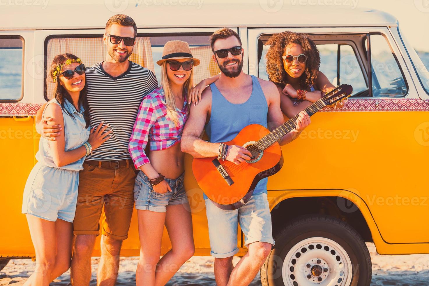 vänner evigt. grupp av ung glad människor stående nära deras retro minibuss och leende foto