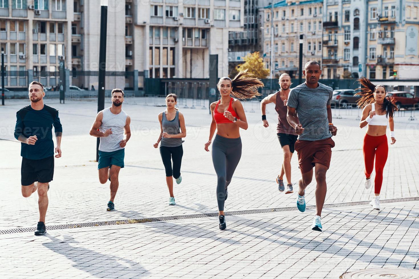 full längd av människor i sporter Kläder joggning medan utövar på de trottoar utomhus foto