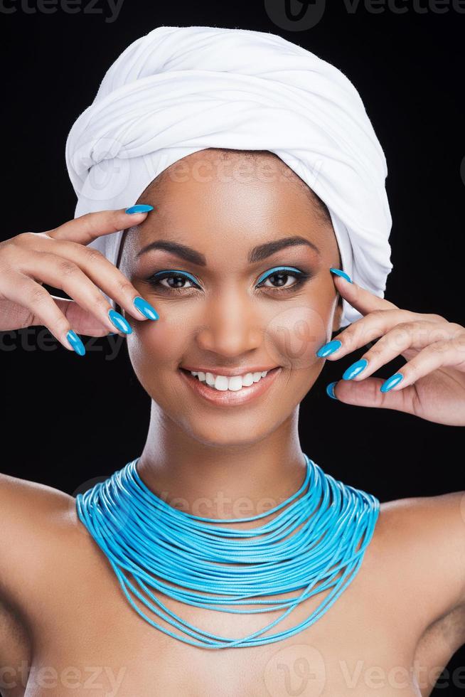 ljus betoning. skön afrikansk kvinna bär vit slöja och leende medan ser på kamera och stående mot svart bakgrund foto