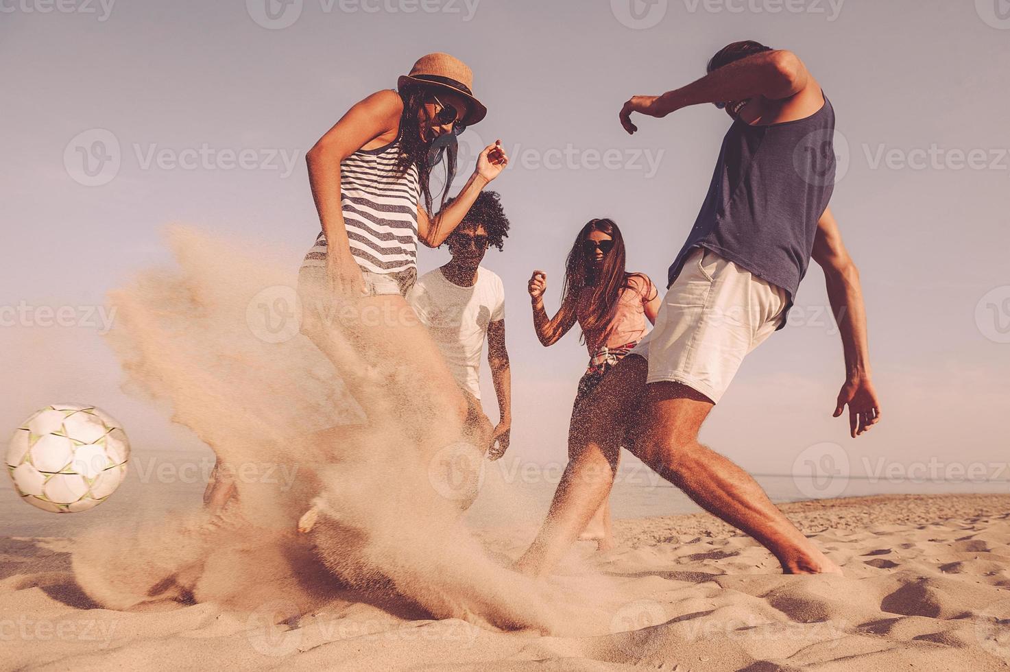 Vad en spel grupp av glad ung människor spelar med fotboll boll på de strand foto